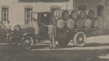 Photo d'archives d'un ancien camion avec des barils, accompagné d'un employé